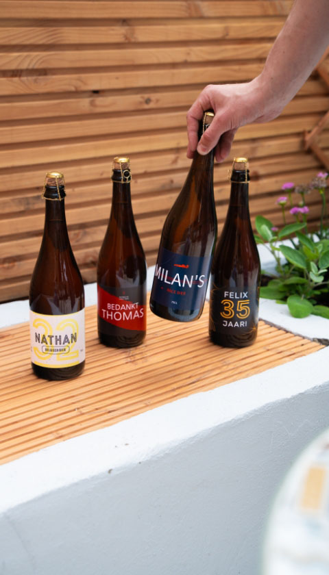 Vier bierflessen met gepersonaliseerde etiketten op bamboe dienblad