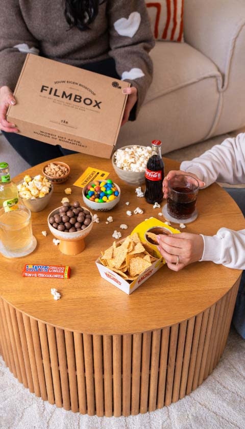 Filmbox cadeau op salontafel met snacks, popcorn en Cola